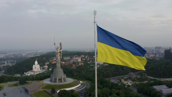 Aerial View of the Ukrainian Flag Waving in the Wind Against the City of Kyiv alt