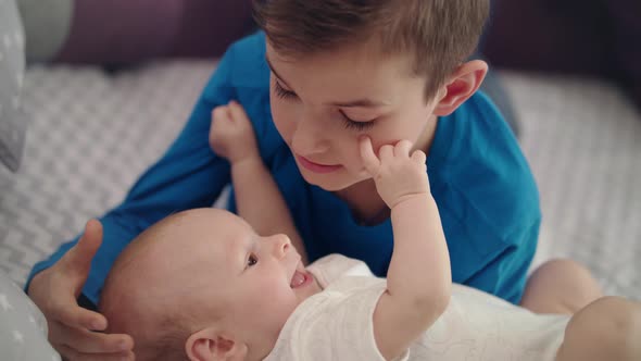 Siblings Have Fun on Bed - Boy Playing with Baby alt