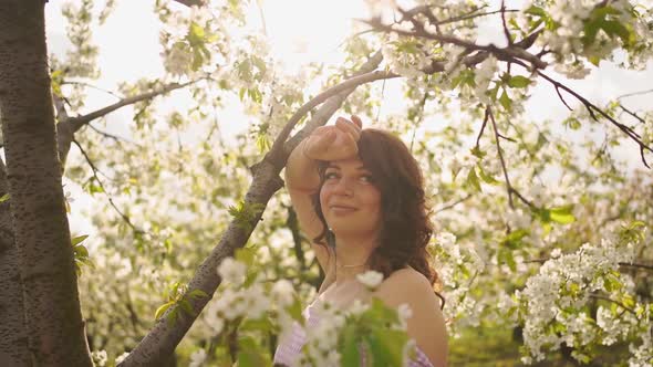 Attractive Woman Near Flowering Tree in Spring Park alt