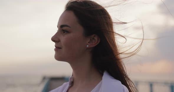 Young Woman Relaxing Looking on the Overcast Windy Sky alt