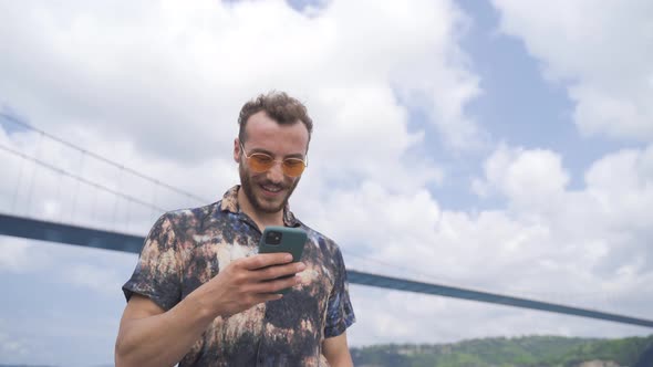 Young man using phone by the sea. alt