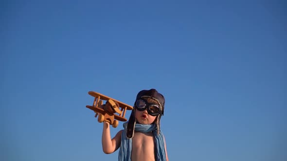 Happy child playing with vintage wooden airplane against blue sky