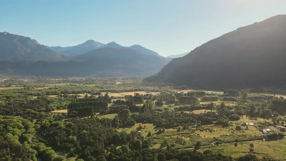 Pan left of El Hoyo valley flying over a beautiful woodland with mountains in background, Chubut, Pa alt