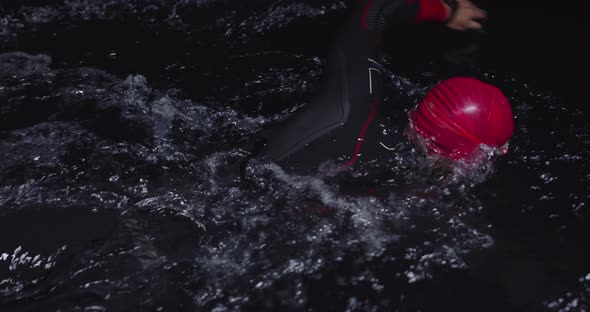 Triathlon Athlete Swimming in Dark Night Wearing Wetsuit alt