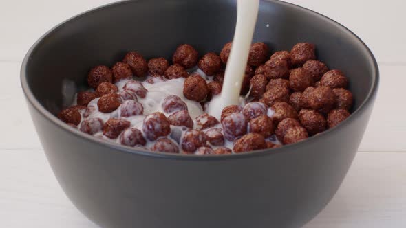Milk Pouring Into a Bowl with Chocolate Balls Cereals for Breakfast