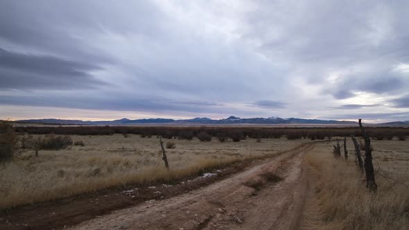 Looking down dirt road during timelapse as clouds move over field alt