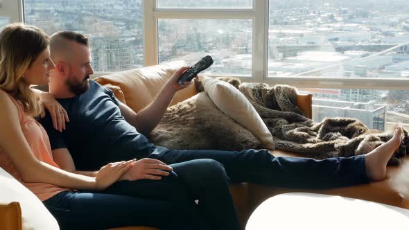 Couple watching television together in living room 4k alt