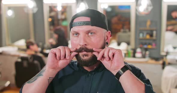 Young Bearded and Mustashed Man with Tattoed Hands with Chin Ring and Tunnel Earrings in Baseball alt