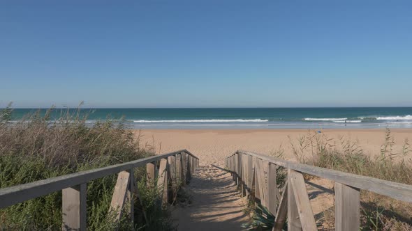 Walking with steadicam on wooden footway on sand of Palmar Beach, Cadiz, Andalucia alt
