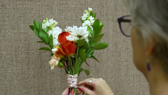 A florist tying and adjusting a ribbon on a bouquet of flowers alt