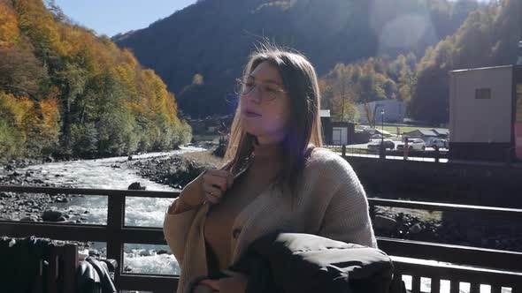 Girl Traveler Crosses an Old One Stands on a Bridge Over a Mountain River on a Bright Autumn Day