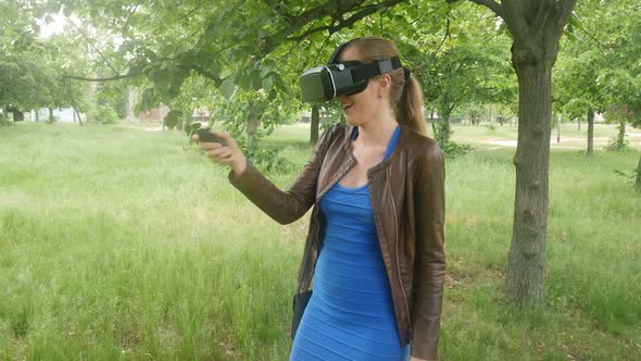 Sexy Girl In A Virtual Reality Helmet Uses A Virtual App In The Park