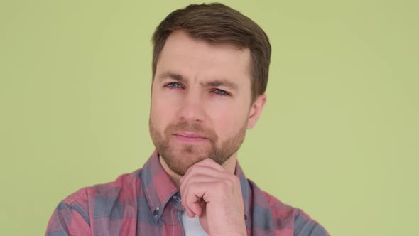 Close Up of a Man with Blue Eyes on a Yellowgreen Background He Looks Intently Straight alt