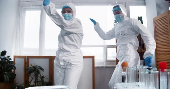 Two Happy Fun Female Scientists Doctors in White Medical Protection Suits Dance Celebrating Success alt