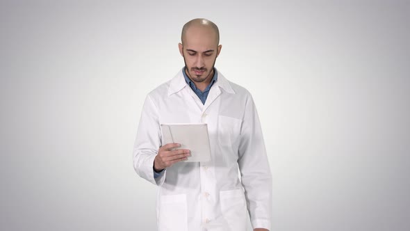 Mature Male Doctor Holding Digital Tablet Using It and Walking on Gradient Background. alt