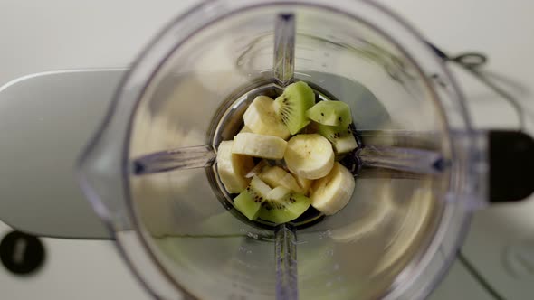 Top Down View Kiwi Chunks are Thrown Into Blender to Make Smoothie alt