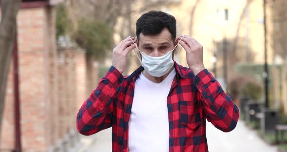 Man wearing medical face mask, looking to camera.