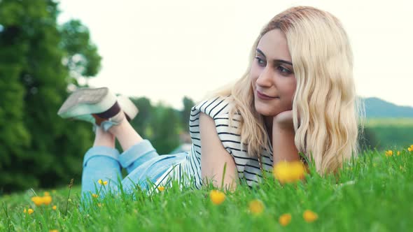 Blonde European Girl Lying on the Grass and Looking Beside alt