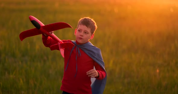 Young Boy Pilot and Runs in Field at Sunset and Playing with Plane Dreaming alt