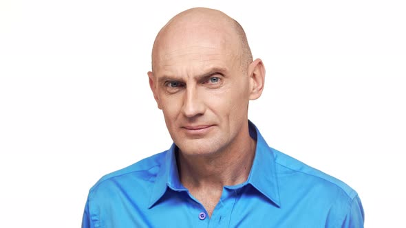 Bold Caucasian Middleaged Male in Blue Shirt Seriously Peering at Camera Standing on White alt