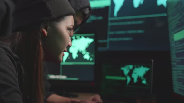 Young Asian Couple Hackers Using Computer Hacking, Code On Multiple Computer Screens alt