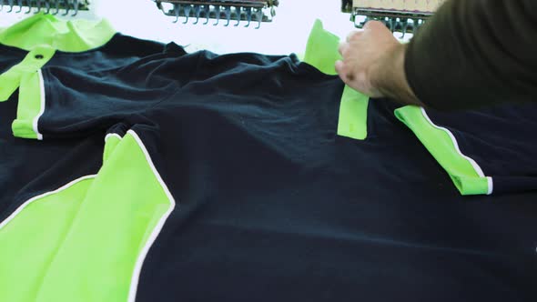 Man in a Textile Factory Checking the Sewing on T-shirt alt