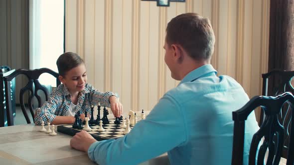 Son playing chess with father at home