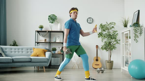 Funny Retro Style Bodybuilder Training with Dumbbell and Bananas Looking at Camera Indoors in alt