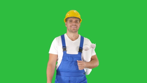 Construction worker walking with blue prints and smiling alt