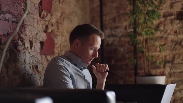 Thoughtful Serious Young Man Student Writer Sit at Home Office Desk with Laptop Thinking of alt