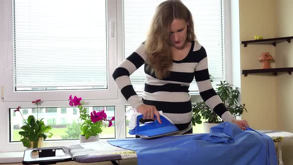 Pregnant Woman Ironing Husband's Shirt on Ironing Board with Vapour