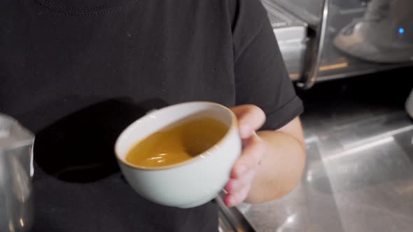 Cropped Shot of a Barista Adding Hot Milk Into Coffee in a Cup