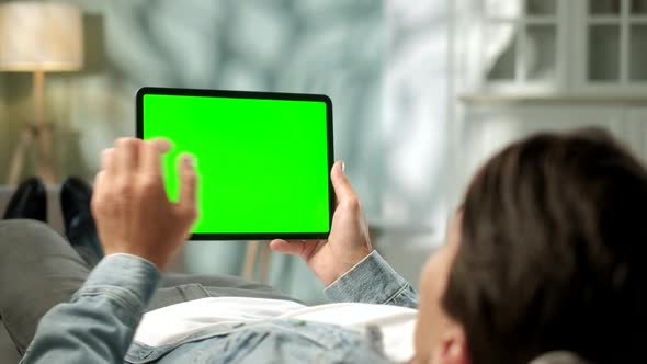 View From the Shoulder of Man Using Hand Gestures on Green Mock-up Screen Digital Tablet Computer in alt