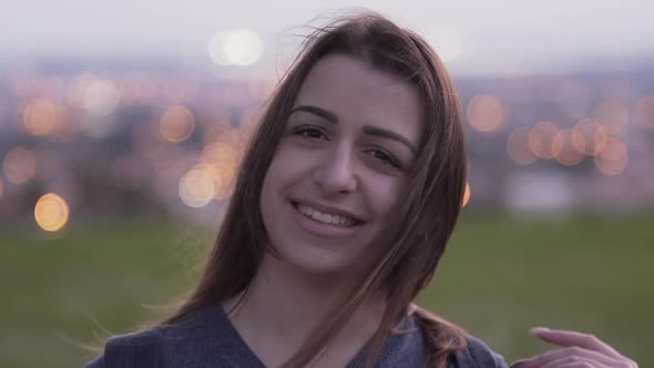 Portrait of Young Smiling Woman with City Lights in Bakcground