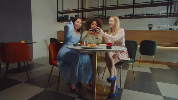 Joyful Multiracial Females Having Fun Dancing at Cafe Table alt