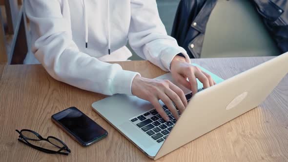 Hands of a Young Caucasian Female Freelancer Using Laptop to Work at a Distance Sitting in a Modern alt