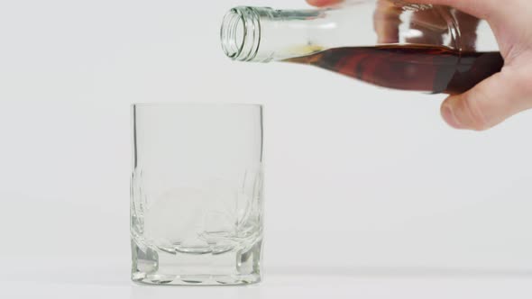 Pouring whiskey from a bottle into glass alt