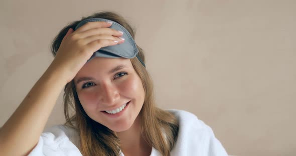 Young Woman Takes Off Black Sleep Mask Sitting By Wall Close