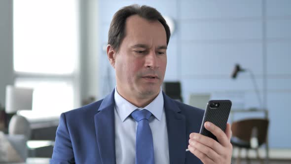 Businessman Reacting To Loss While Using Smartphone alt