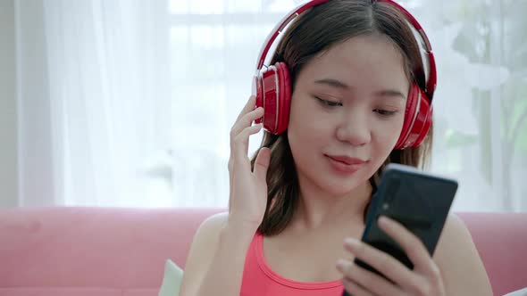 Young Asian woman in sportswear uses her smartphone and headphones