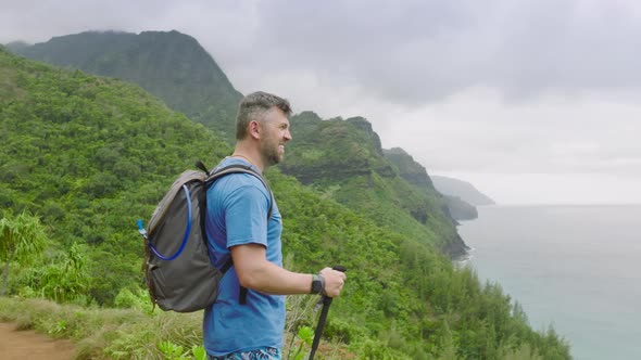 Hiker Raising Arms Up in Air Holding Hiking Walking Sticks at Napali Coast Park alt
