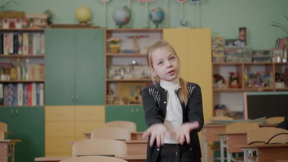 A Young Girl Tells a Story in a School Class and Gestures with Her Hands