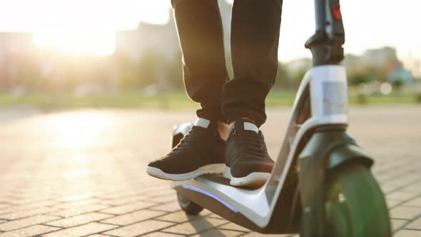 Modern Man in Black Sneakers Using Electric Scooter in Sunny Day Eco Friendly Transportation alt