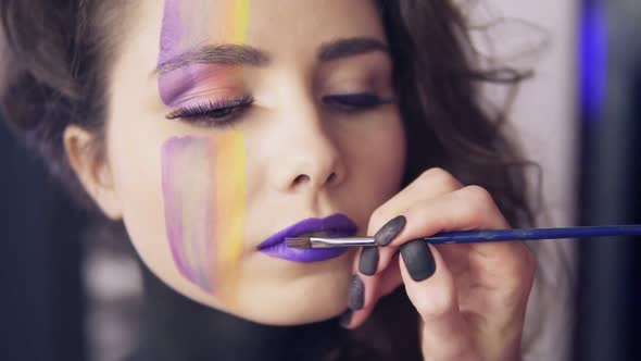 Makeup Artist Uses Brush to Apply Lipstick to Model's Lips alt