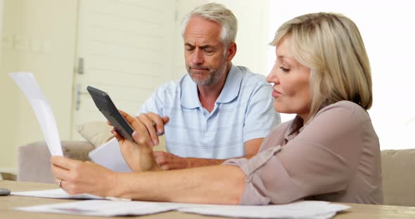Stressed couple working out their finances on the couch alt
