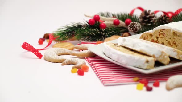 Sliced Traditional Christmas Stollen Cake on Ceramic Plate and New Year Decorations alt