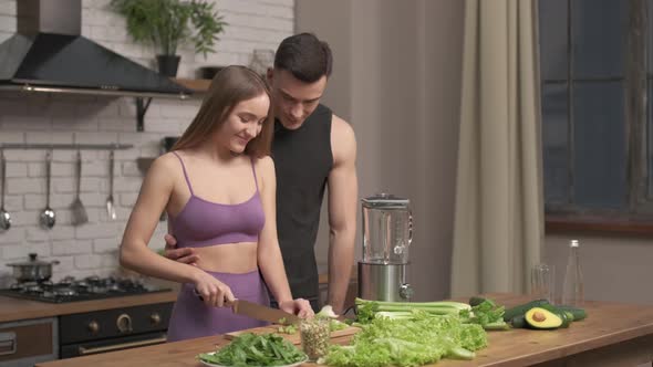 muscular young couple cooking healthy cocktail after workout, talking and laughing in the kitchen.  alt