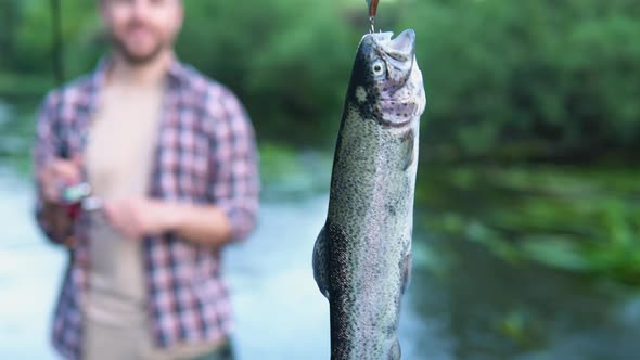 Fisherman Rests on the River and Catches Trout Smiles and Shows the Fish in the Camera alt