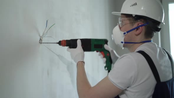 A Worker Builder on a Construction Site with a Punch Makes Repairs to an Apartment or a House
