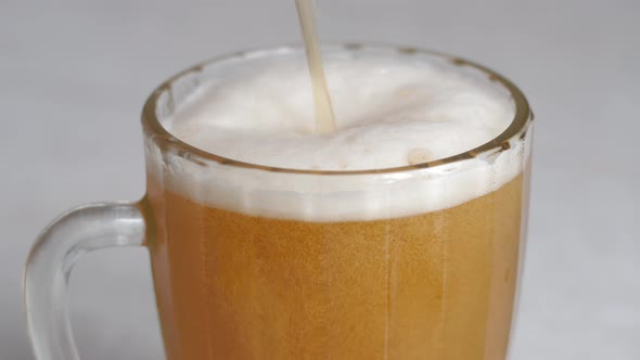 Close-up of beer with a lot of foam being poured into a large bar mug. drinking beer concept. beer b alt